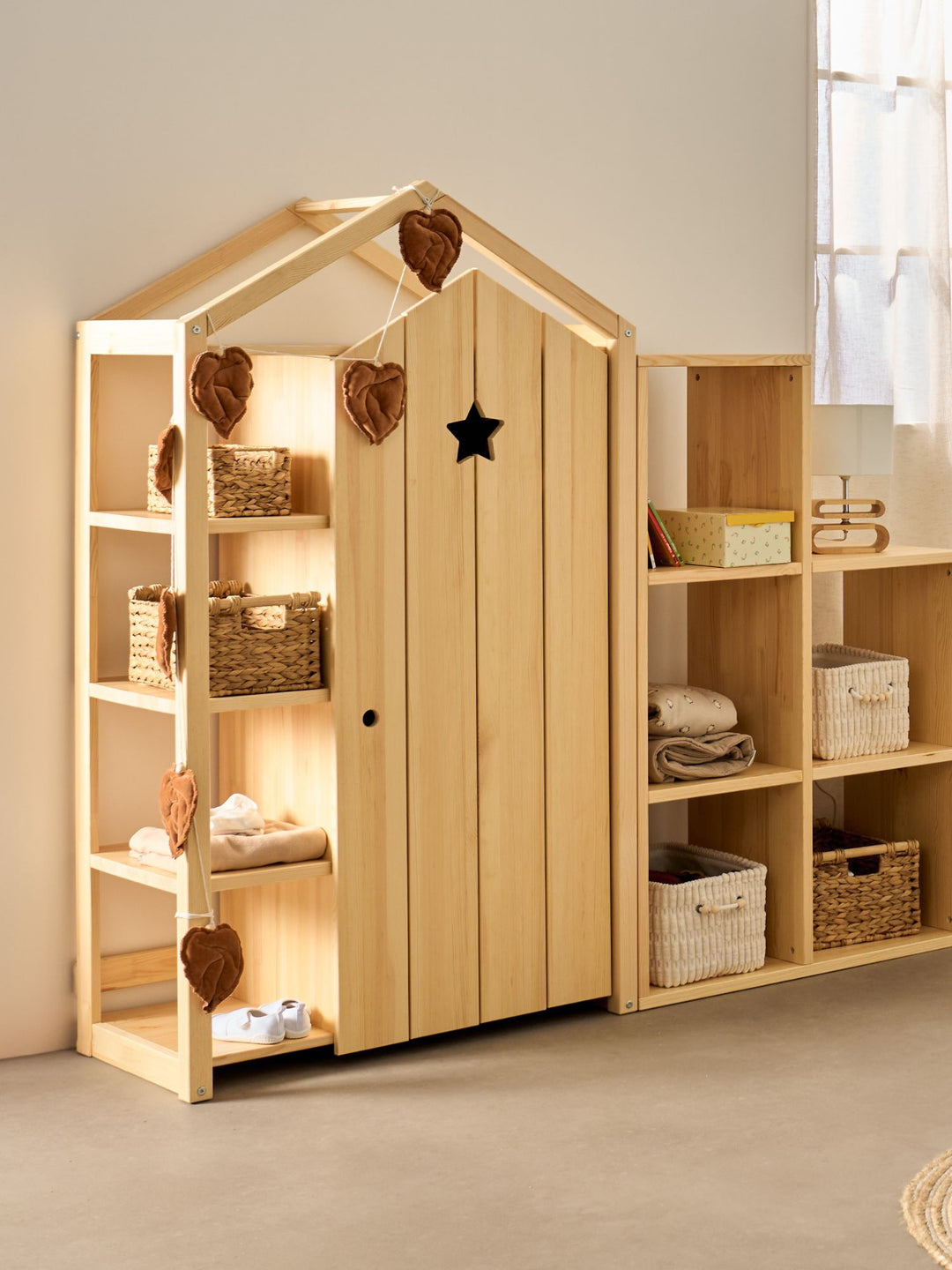 Armoire enfant Cabania en forme de cabane, porte étoile et étagères latérales, près de cubes de rangement