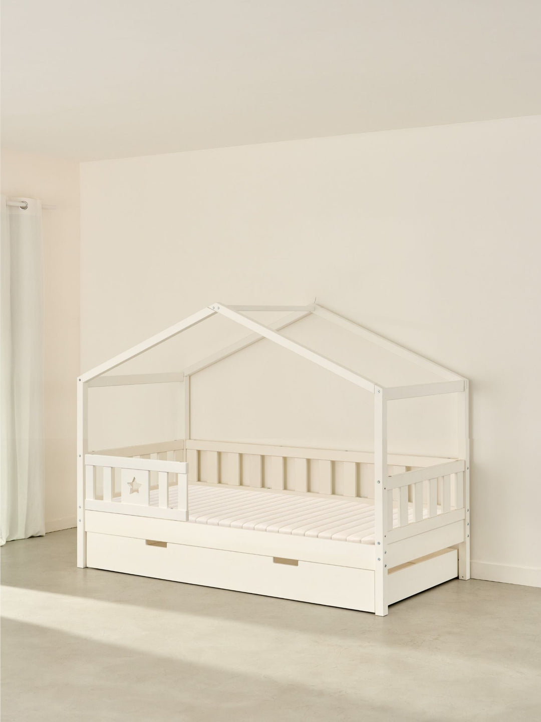 Lit cabane enfant blanc Paris Cabania avec barrière étoile et tiroir de rangement intégré.