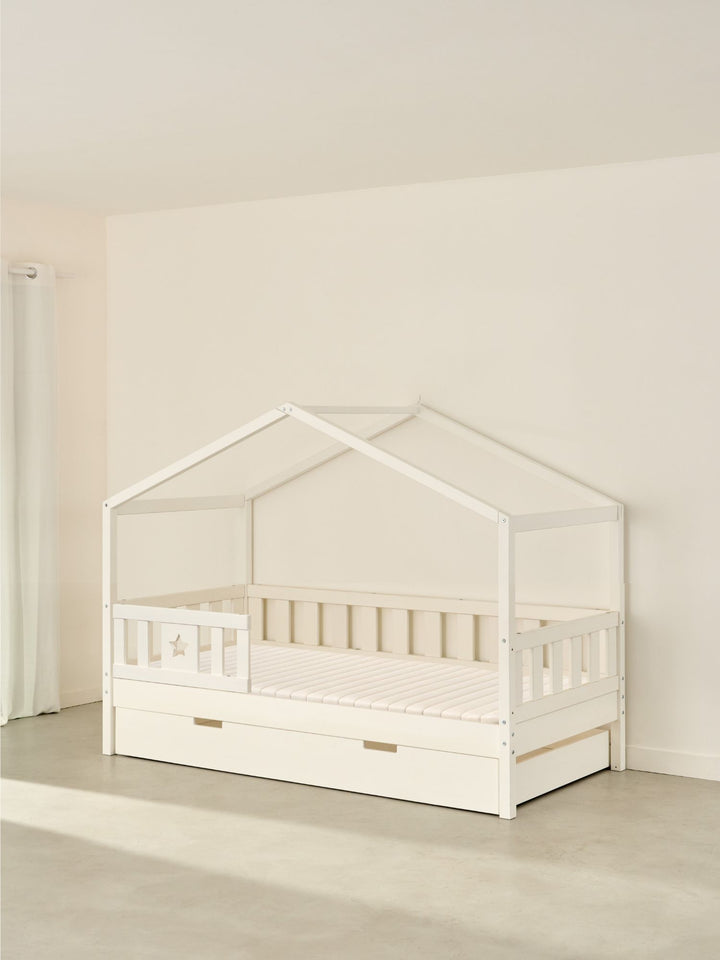 Lit cabane enfant blanc Paris Cabania avec barrière étoile et tiroir de rangement intégré.
