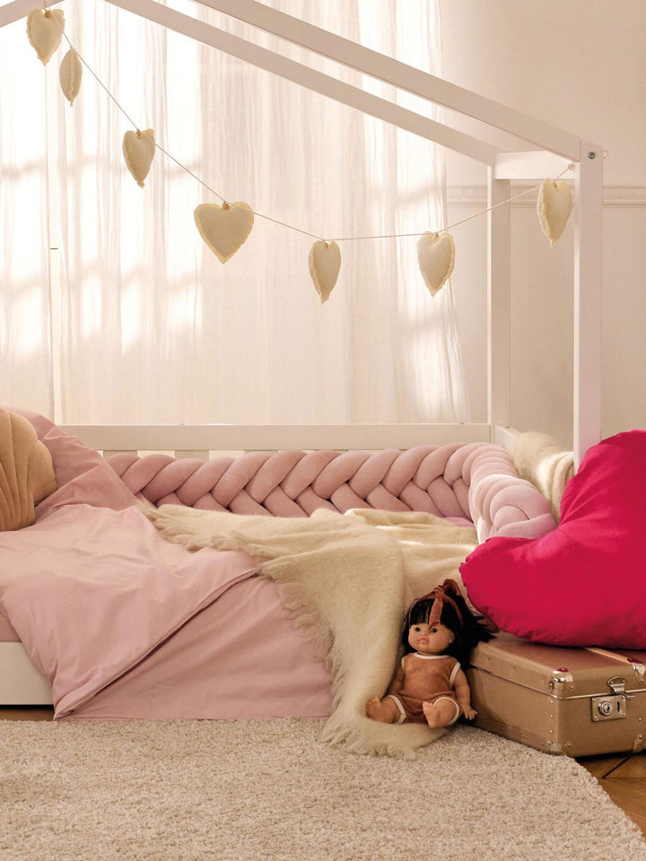 Tresse de lit en velours installée sur un lit cabane blanc, avec guirlande de cœurs