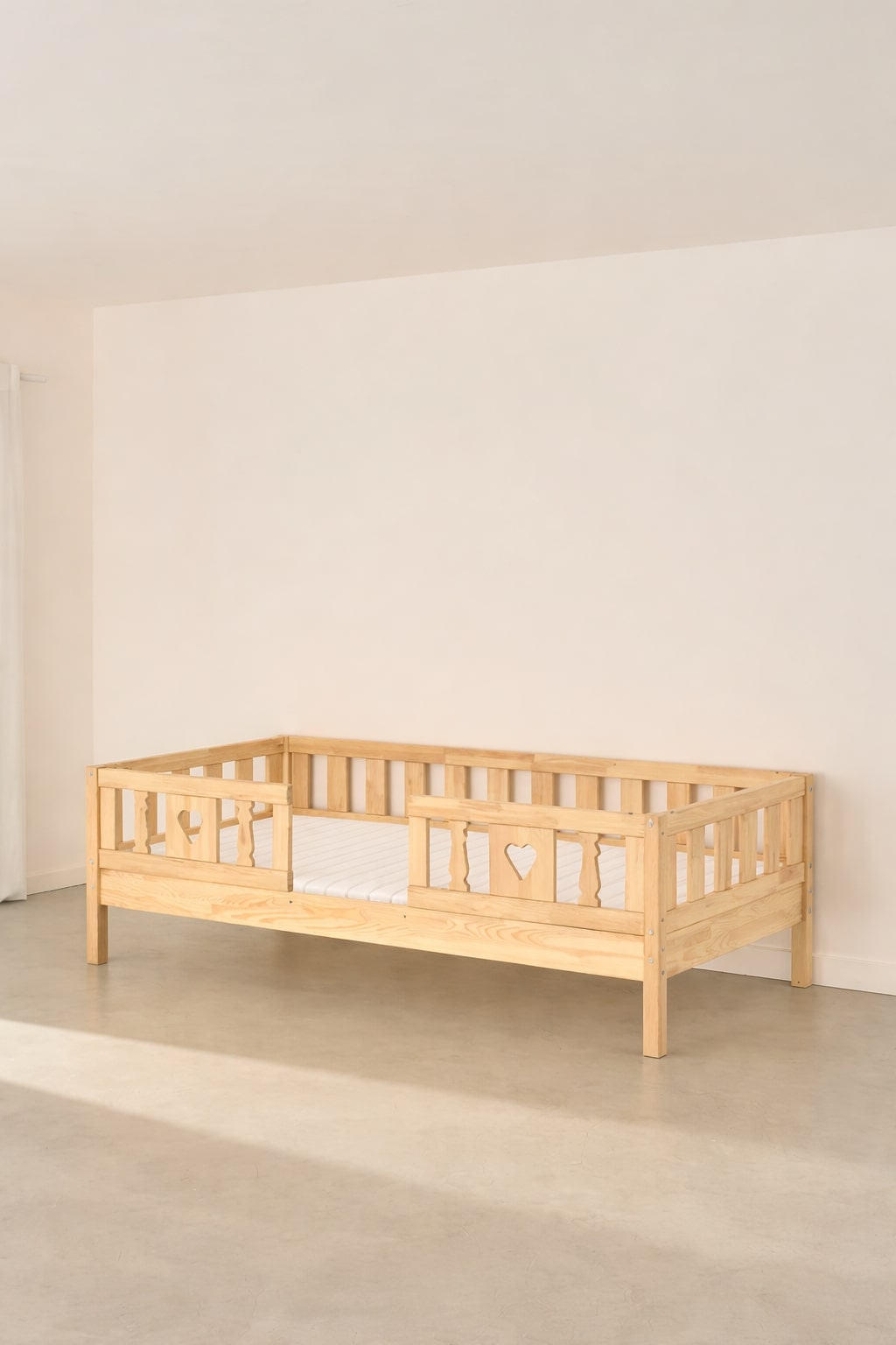 Barcelona natural wood convertible children's bed with two heart-patterned safety rails.