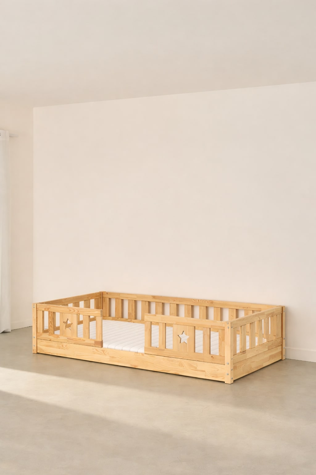 Barcelona Montessori convertible bed in natural wood with two star-shaped safety rails for children.